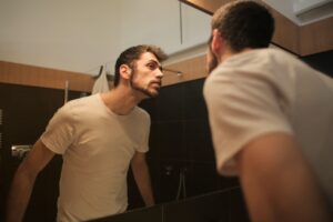 Hombre revisando su barba frente al espejo.