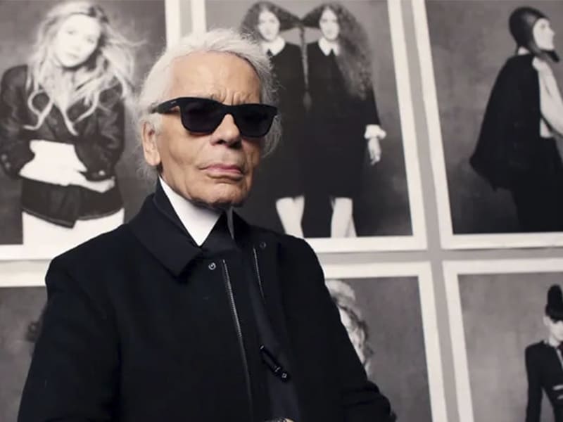 El diseñador Karl Lagerfeld posando delante de una muestra de fotos inspirada en su obra.